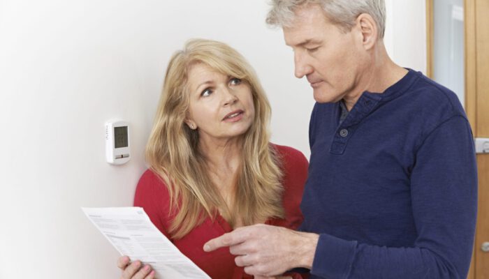 Worried Mature Couple With Bill Turning Down Central Heating