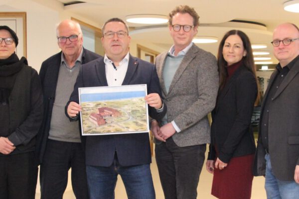 Landrat Dr. Axel Lehmann hält eine vergrößerte, historische Postkarte in den Händen, die das ehemalige „Jugendwerk Detmold“ auf Norderney zeigt.